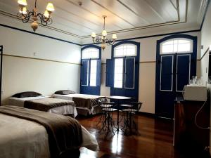 a room with two beds and a table and chairs at Suíte Marília de Dirceu in Ouro Preto