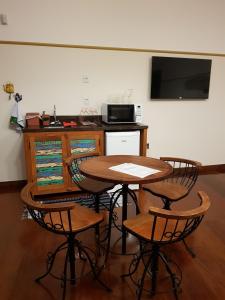 uma mesa e cadeiras numa cozinha com uma televisão em Suíte Marília de Dirceu em Ouro Preto
