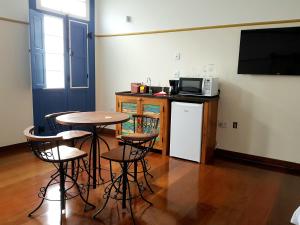 a kitchen with a table and chairs and a microwave at Suíte Marília de Dirceu in Ouro Preto