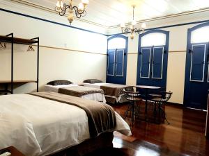 um quarto com três camas e uma mesa com cadeiras em Suíte Marília de Dirceu em Ouro Preto