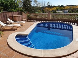una piscina con 2 sillas de césped y una piscina en Cal Llopet, en Can Cartro