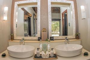 two sinks in a bathroom with two mirrors at Thornybush Simbambili Lodge in Sabi Sand Game Reserve