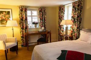 a bedroom with a bed and a desk and windows at Romantik Hotel Zum Rosenhof in Hesserode
