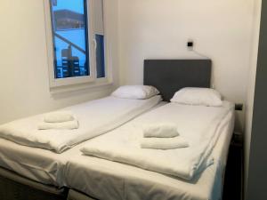 two twin beds in a room with a window at Brygga Gjestehus in Harstad