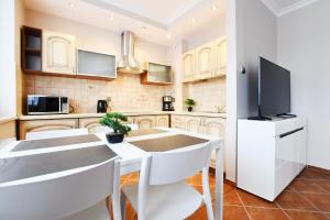 Il comprend une cuisine avec une table et des chaises ainsi qu'une télévision. dans l'établissement MIZU Apartamenty - Zielone Tarasy, à Kołobrzeg