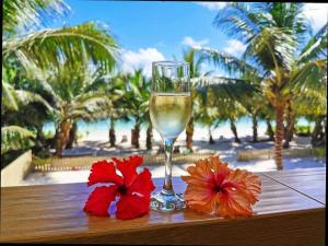 un bicchiere di vino e due fiori rossi su un tavolo di Seashell Beach Villa a Grand'Anse Praslin