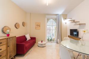 uma sala de estar com um sofá vermelho e uma mesa de vidro em GR0-Quiet apartment, Private backyard, Walk to Old Town em Málaga