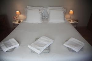 a large white bed with white pillows and towels at La Maison De Maria in Folembray