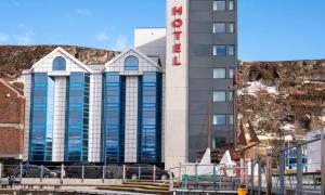 a hotel with cars parked in front of a building at Thon Hotel Hammerfest in Hammerfest