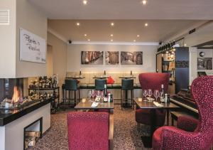 a bar with red chairs and tables and a fireplace at Rhein-Hotel Nierstein in Nierstein