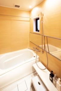 La salle de bains est pourvue d'une baignoire et d'un miroir. dans l'établissement カモンイン 東寺道, à Kyoto