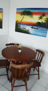 una mesa de madera con sillas y una pintura en la pared en Edificio Verano, en Natal