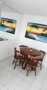 una mesa y sillas en una habitación con pinturas en la pared en Edificio Verano, en Natal