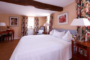a bedroom with a large white bed and a desk at Romantik Hotel Zum Rosenhof in Hesserode