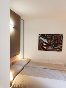 a bedroom with two beds and a painting on the wall at Dimora diffusa Sannicolò al Fiume in Rovereto