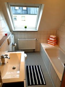 ein Bad mit einem Waschbecken, einer Badewanne und einem Fenster in der Unterkunft Wohlfühl-Apartment Bad Kissingen III in Bad Kissingen