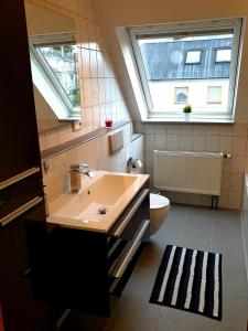 a bathroom with a sink and a toilet and two windows at Wohlfühl-Apartment Bad Kissingen III in Bad Kissingen