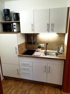 eine Küche mit weißen Schränken und einem Waschbecken in der Unterkunft Wohlfühl-Apartment Bad Kissingen III in Bad Kissingen