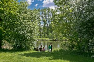 a group of people sitting on a bench near a lake at KNAUS Campingpark Frickenhausen in Frickenhausen