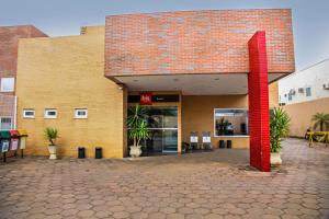 Um edifício de tijolos com um poste vermelho à frente. em ibis Bacabal em Bacabal