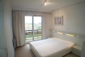 a bedroom with a bed and a large window at Oostduinkerke Apartments in Oostduinkerke