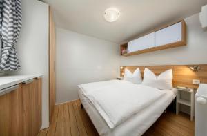 a bedroom with a white bed and a window at KNAUS Campingpark Frickenhausen in Frickenhausen