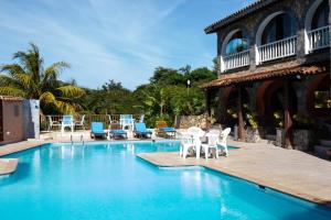 una piscina con sillas blancas y una casa en Colonna Park Hotel, en Búzios