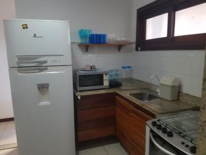 uma cozinha com um frigorífico branco e um lavatório em Porto das Baleias Praia do Forte em Praia do Forte