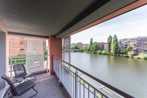 a balcony with two chairs and a view of a river at Zefiro Chmielna in Gdańsk