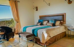 ein Schlafzimmer mit einem Bett und einem Stuhl und einem Fenster in der Unterkunft Zebula 8 Bedroom Lodge – IV1 in Mabula
