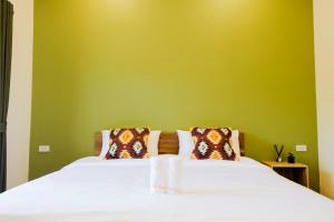 a bedroom with a white bed with a green wall at The Cozy Hotel in Phetchaburi
