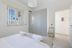 a white bedroom with a bed and a window at Villa Diamante by BarbarHouse in Maruggio