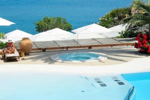 a woman sitting in a chair next to a swimming pool at Le Calette Bay in Cefalù