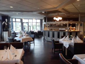 un restaurant avec des tables et des chaises blanches et un bar dans l'établissement Fletcher Hotel - Restaurant Nieuwvliet Bad, à Nieuwvliet-Bad