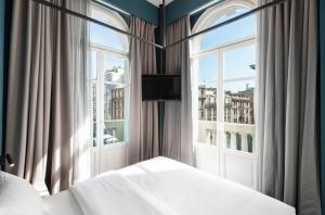 a bedroom with a bed and two large windows at Colors Urban Hotel Thessaloniki in Thessaloniki