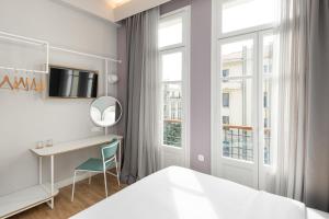 a bedroom with a bed and a desk and a window at Colors Urban Hotel Thessaloniki in Thessaloniki