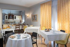 un restaurante con mesas y sillas blancas y una cocina en Seven Suites Pieve, en Pieve di Soligo
