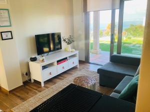 ein Wohnzimmer mit einem Flachbild-TV auf einem weißen Schrank in der Unterkunft Casa con jardín al lado de Playa Hío in Vilanova