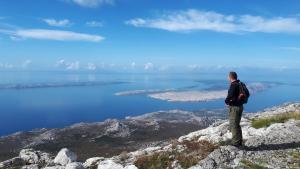 a man standing on top of a mountain looking at the water at Apartments Tomas in Senj