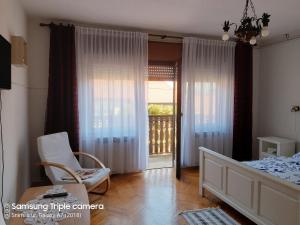 een slaapkamer met een bed en een stoel en een balkon bij Rooms & Apartments Amelee in Zagreb