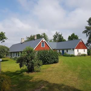 a barn with a red and white house in a field at 4B Österlen Bed & Breakfast in Tomelilla