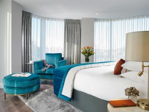 a hotel room with a bed and two blue chairs at Fairways Hotel Dundalk in Dundalk