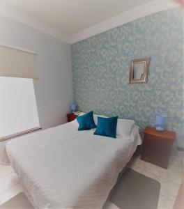 a bedroom with a white bed with blue walls at Hotel Vista Hermosa 17 in Viña del Mar