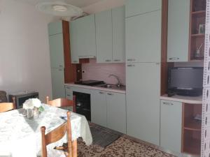 a kitchen with white cabinets and a table with a television at Al mare con vista codice CITRA 009049-LT-0787 in Pietra Ligure +12 photos