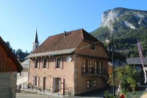 un edificio frente a una montaña con una iglesia en Le postillon - Duo en Saint-Pierre-dʼEntremont