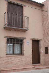 a brick building with a balcony and a door at El Cañizar in Villarquemado