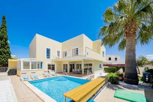 a villa with a swimming pool and a palm tree at Porto de Mos 95 by Destination Algarve in Porto de Mós