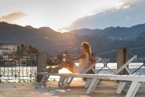 a woman sitting on a picnic table near the water at B&B Al Dom in Orta San Giulio