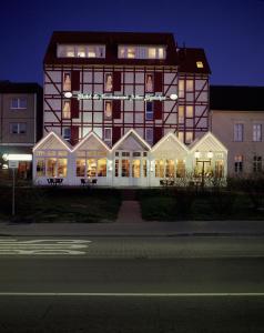 - un grand bâtiment avec des fenêtres éclairées la nuit dans l'établissement Hotel & Restaurant Alter Speicher, à Greifswald