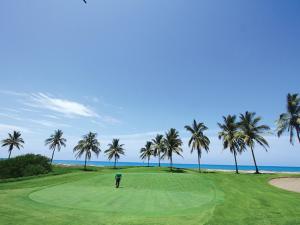 un hombre parado en un campo de golf con palmeras en Luxury Suites By Estrella del Mar en Mazatlán